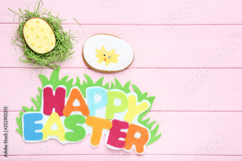 Text Happy Easter with gingerbread cookies on pink wooden table