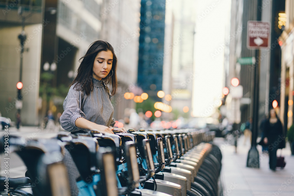 Fototapeta premium girl renting a city bike from a bike stand in chicago