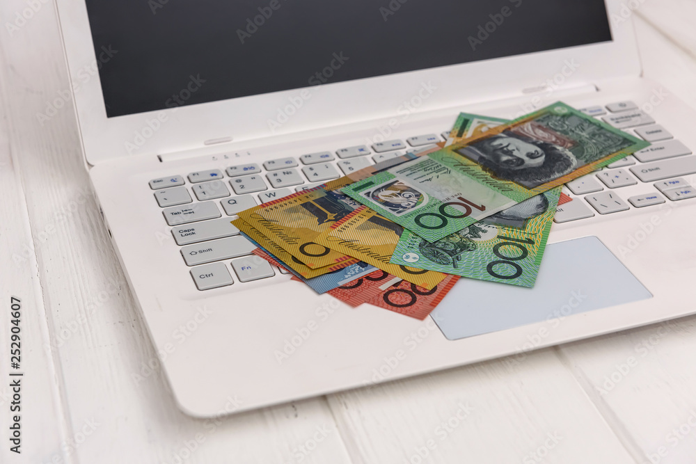 Australian dollar banknotes on white laptop keyboard Australian dollar banknotes on white laptop keyboard