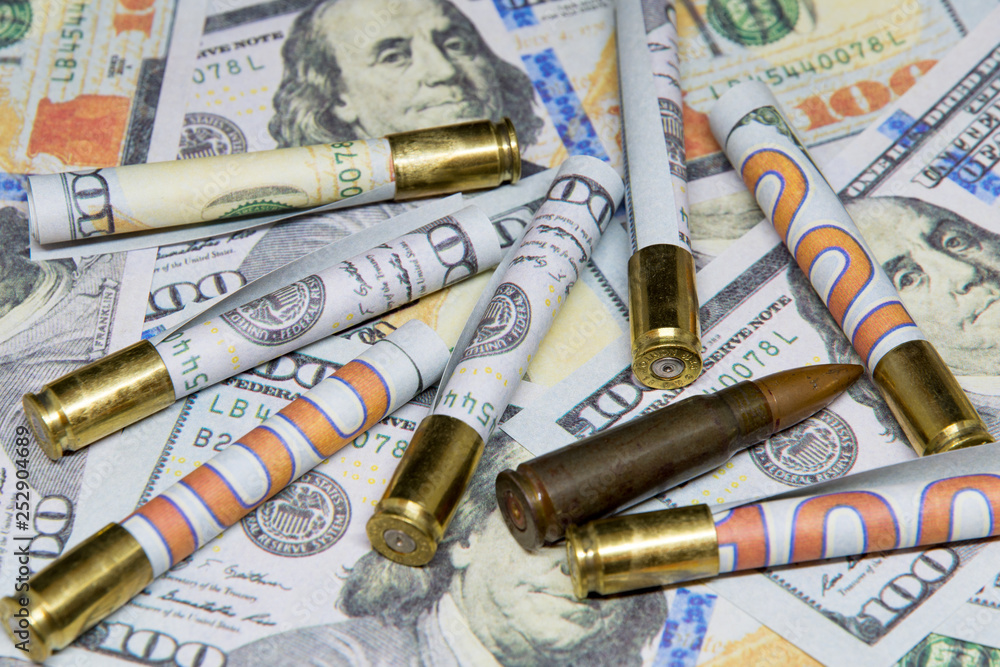 rolled banknotes of dollars inside cartridges over hundred dollar bills money and war concept rolled banknotes of dollars inside cartridges over hundred dollar bills money and war concept