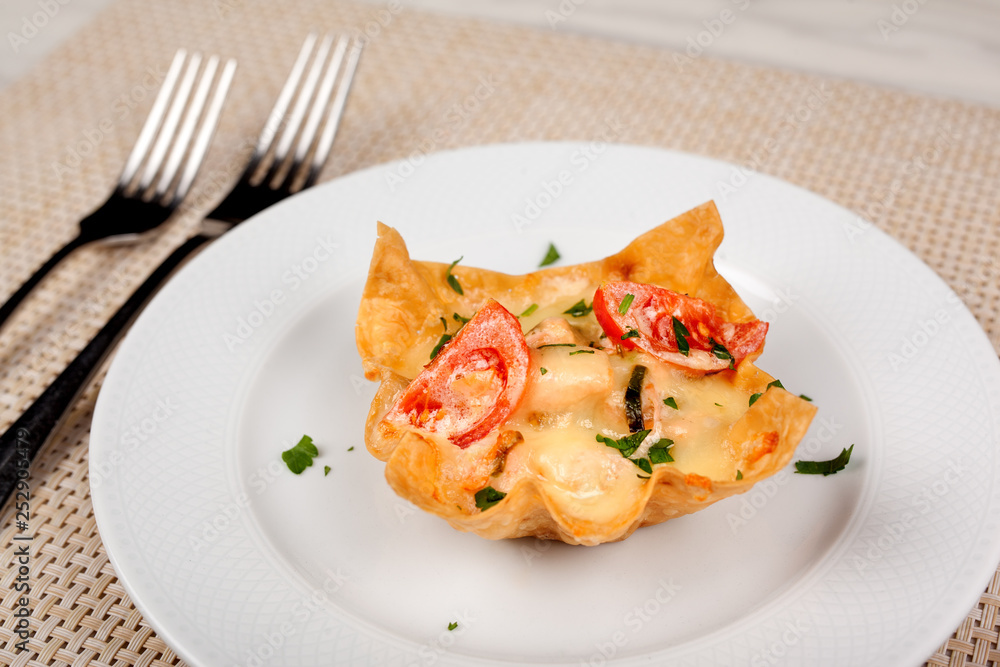 Snack with tomato baked in the dough with cheese on a white plate. Snack with tomato baked in the dough with cheese on a white plate.