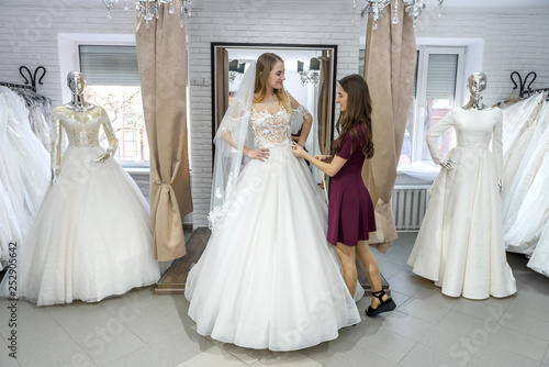 Tailor measuring wedding dress on bride in store