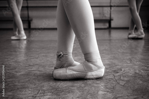 Close-up of ballerina feet on pointe shoes in the dance hall. Vintage photography. Close-up of a ballerina in the dance hall. Black and white photography.