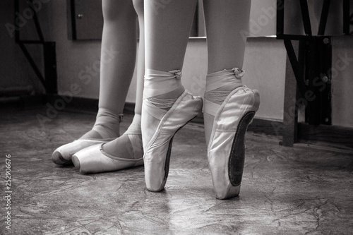 Close-up of ballerina feet on pointe shoes in the dance hall. Vintage photography. Close-up of a ballerina in the dance hall. Black and white photography.
