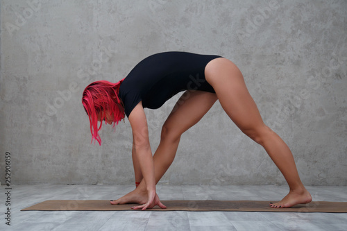 A girl with pink hair practices yoga.