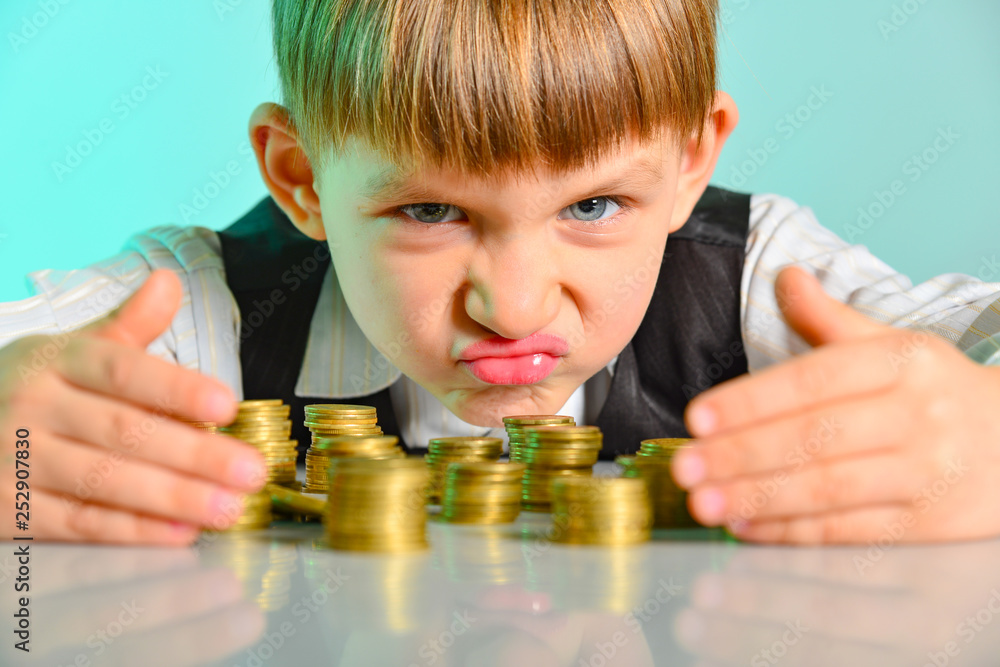 Angry and greedy child holds their money coins. The concept of greed, greed  and vice from childhood Photos