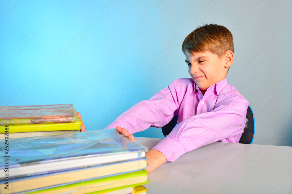 The pupil pushes the textbooks off with his hands, the tortured schoolboy does not like to learn The pupil pushes the textbooks off with his hands, the tortured schoolboy does not like to learn