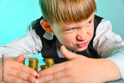 фотографія An angry and greedy little boy hides his cash savings
