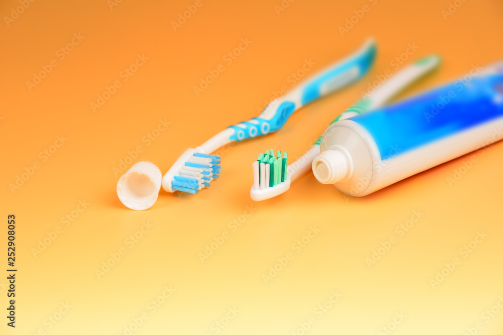 Two toothbrushes and a tube of toothpaste are close-ups on a yellow background in the studio Two toothbrushes and a tube of toothpaste are close-ups on a yellow background in the studio