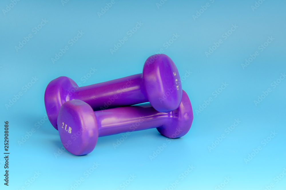 Purple dumbbells for sports on a blue background Purple dumbbells for sports on a blue background