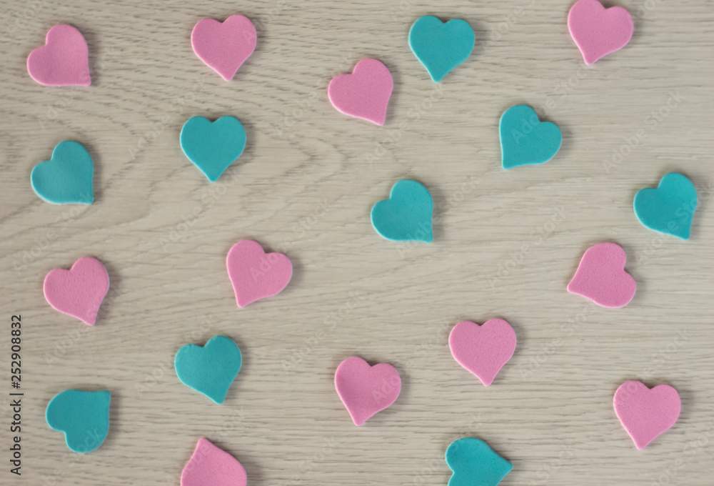 Small hearts of pink and blue color lie on a white wooden table. Small hearts of pink and blue color lie on a white wooden table.