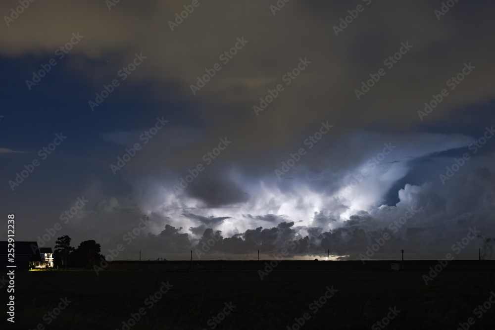 An autumn thunderstorm over the dutch countryside. The anvil of the storm is clearly visible while illuminated by lightning. An autumn thunderstorm over the dutch countryside. The anvil of the storm is clearly visible while illuminated by lightning.