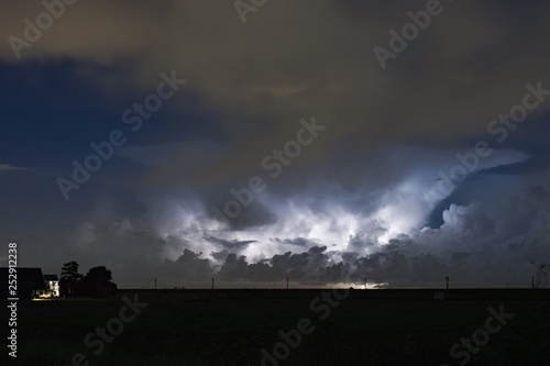 An autumn thunderstorm over the dutch countryside. The anvil of the storm is clearly visible while illuminated by lightning. 