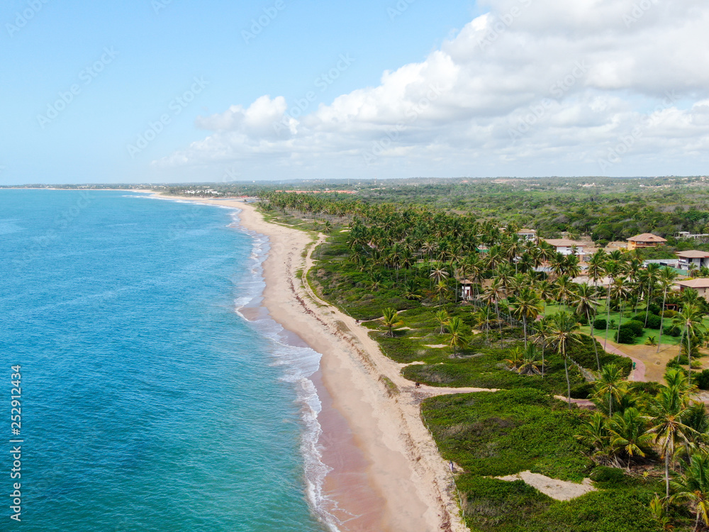 Aerial view of tropical white sand beach and turquoise clear sea water with small waves and palm trees background. Praia do Forte, Bahia, Brazil. Travel tropical concept Aerial view of tropical white sand beach and turquoise clear sea water with small waves and palm trees background. Praia do Forte, Bahia, Brazil. Travel tropical concept