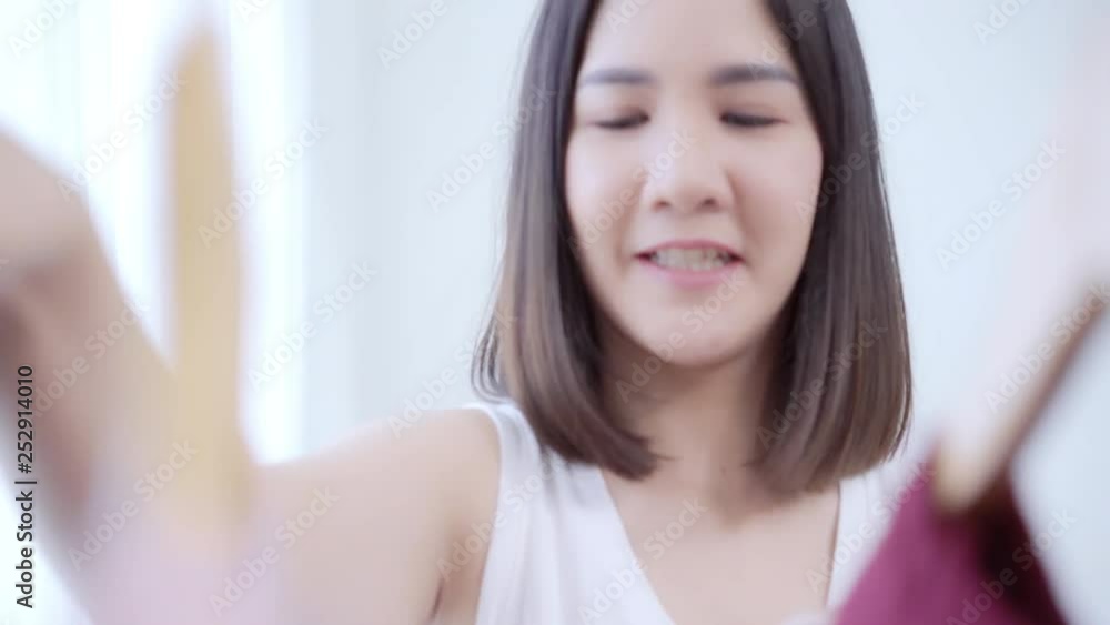 Beautiful attractive young Asian woman choosing her fashion outfit clothes in closet at home or store. Girl think what to wear sweater. Home wardrobe or clothing shop changing room. Beautiful attractive young Asian woman choosing her fashion outfit clothes in closet at home or store. Girl think what to wear sweater. Home wardrobe or clothing shop changing room.