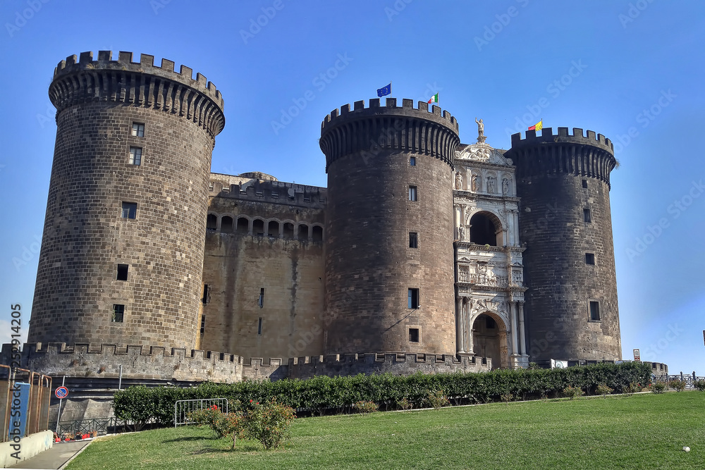 Old stone Maschio Angioino castle in a modern European city. Fort in Naples. Sunny day with blue sky