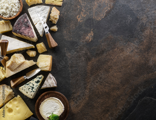 Assortment of organic cheeses on stone background. Top view. Tasty cheese starter.