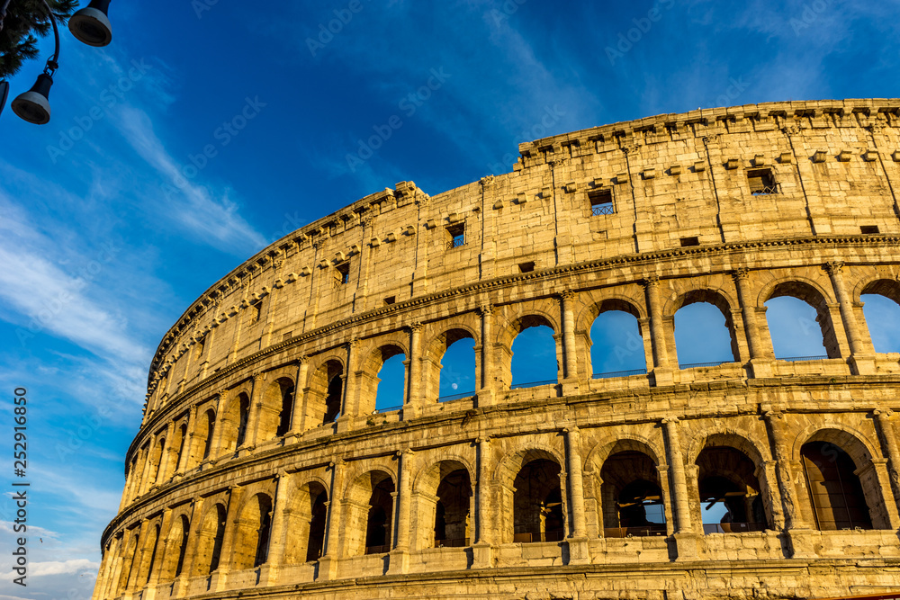 Golden sunset at the Great Roman Colosseum (Coliseum, Colosseo), also known as the Flavian Amphitheatre. Famous world landmark. Scenic urban landscape.