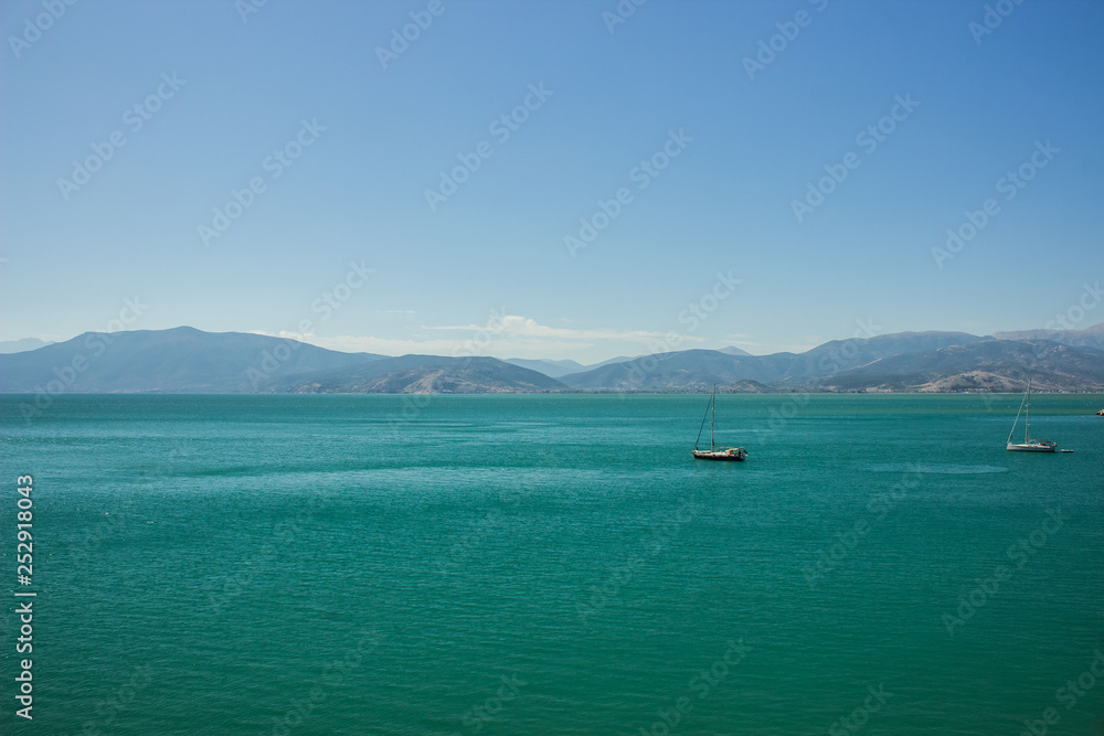 picturesque vivid colorful south sea landscape scenery view with mountain horizon background and two yachts on calm green blue water surface 