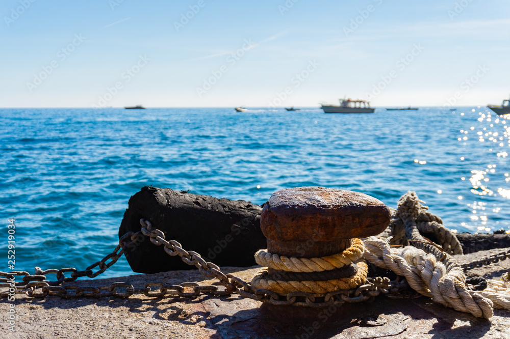 Fototapeta premium Mooring rope and old bollard on sea water and yachts background