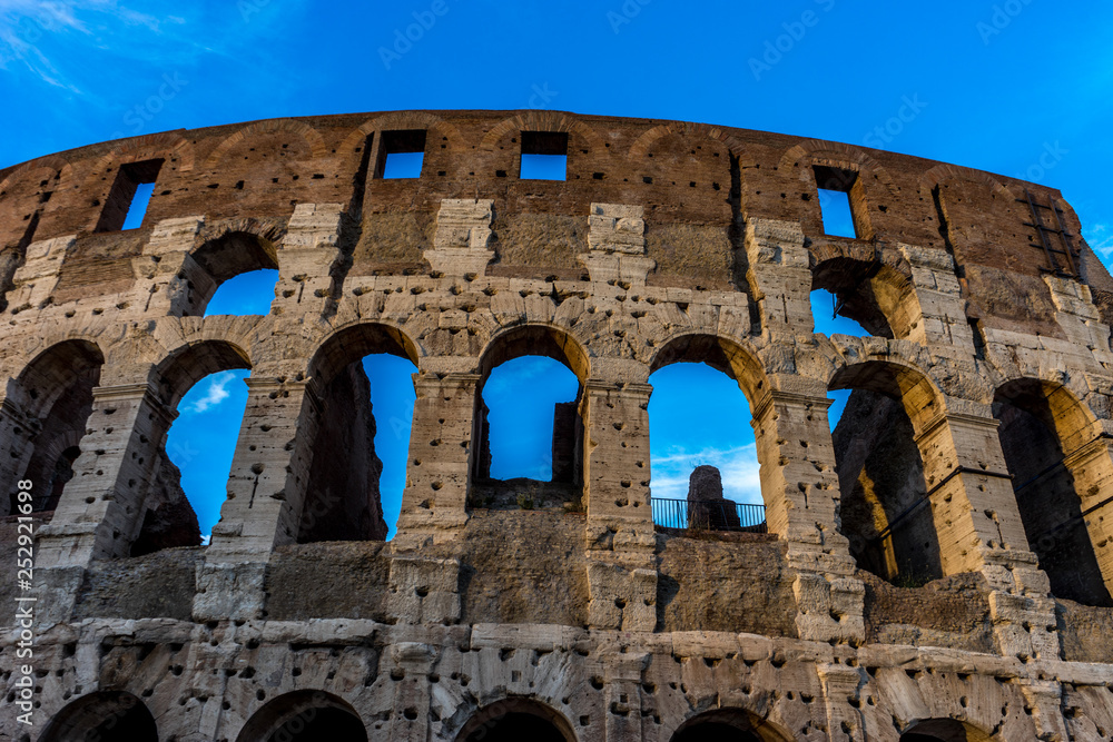 Golden sunset at the Great Roman Colosseum (Coliseum, Colosseo), also known as the Flavian Amphitheatre. Famous world landmark. Scenic urban landscape.