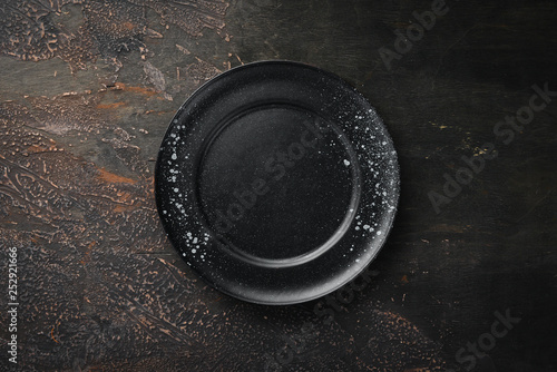 Black plate on a dark background. Top view. Free copy space.
