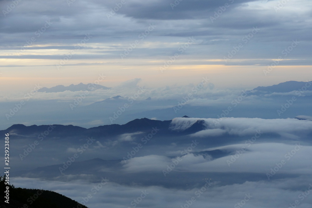 Obraz premium Clouds flowing over mountain tops, seen from Mount Fuji at dusk, Japan
