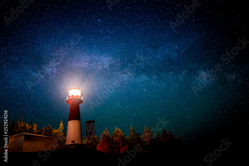 Fototapeta A lighthouse at night with a star filled sky above