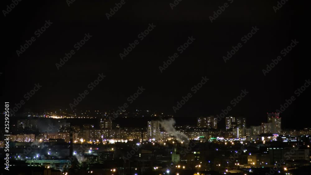Night city skyline timelapse. Top aerial panoramic view of modern city from tower rooftop. Road junction traffic. Lights flicker in windows. Residential flats,factory pipes with smoke Night city skyline timelapse. Top aerial panoramic view of modern city from tower rooftop. Road junction traffic. Lights flicker in windows. Residential flats,factory pipes with smoke