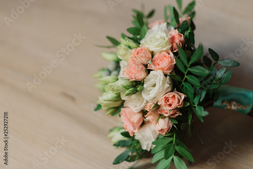 Wedding bouquet lying on grey carpet during preparation before celebration. Side view of decorative rose flowers and leaves bouquet. Marriage decoration of flowers bouquet