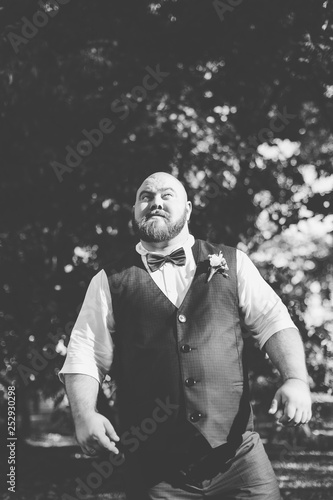 Stylish bearded fat groom in the park.