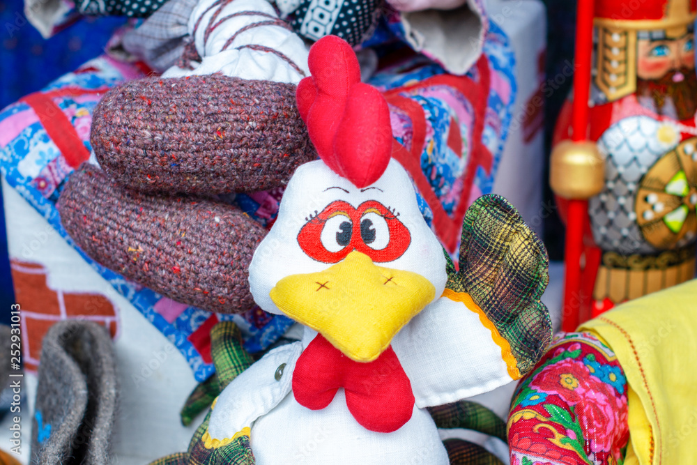 a bright rooster with a red scallop made of handmade fabric at an exhibition for sale on the street