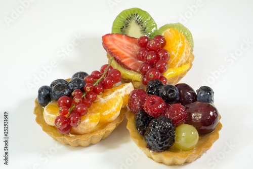 Three cakes with fresh bio fruits, orange, kiwi, strawberries, blueberries, red currants, grapes, raspberries, blackberries, side photo, white background, isolate