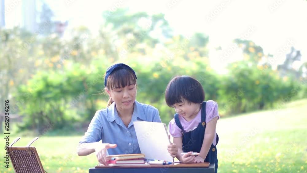Asian family with Mother and daughter write on notebook. Happy enjoy having fun in nature or park and sunlight. Slow Motion Asian family with Mother and daughter write on notebook. Happy enjoy having fun in nature or park and sunlight. Slow Motion