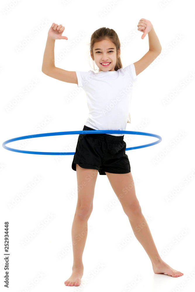 A little girl in a white T-shirt performs exercises with a hoop. A little girl in a white T-shirt performs exercises with a hoop.