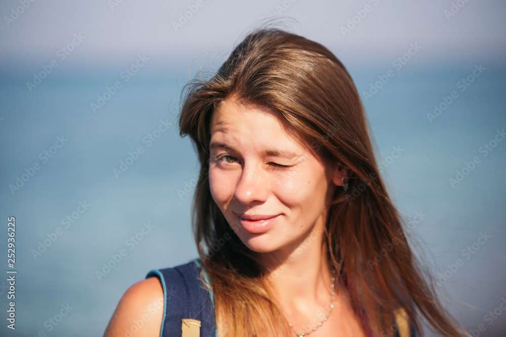portrait of smiling pretty girl with long hair  standing on the beach