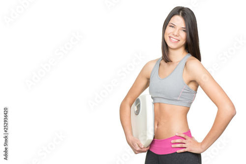 Diet and exercise. Portrait of a young fitness woman holding scales and smiling happily isolated on white copyspace on the side © Nestor