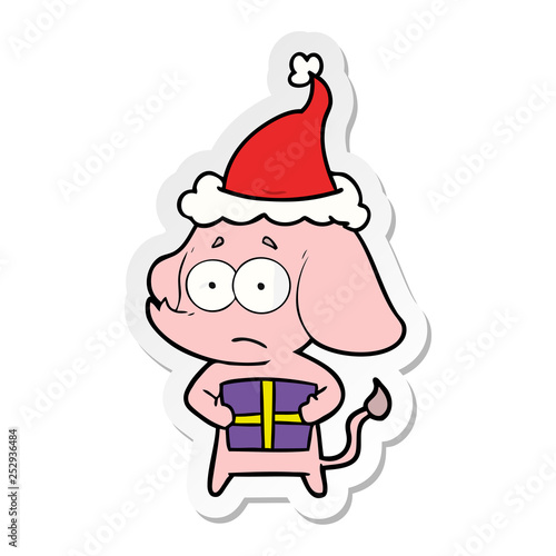 sticker cartoon of a unsure elephant with christmas present wearing santa hat