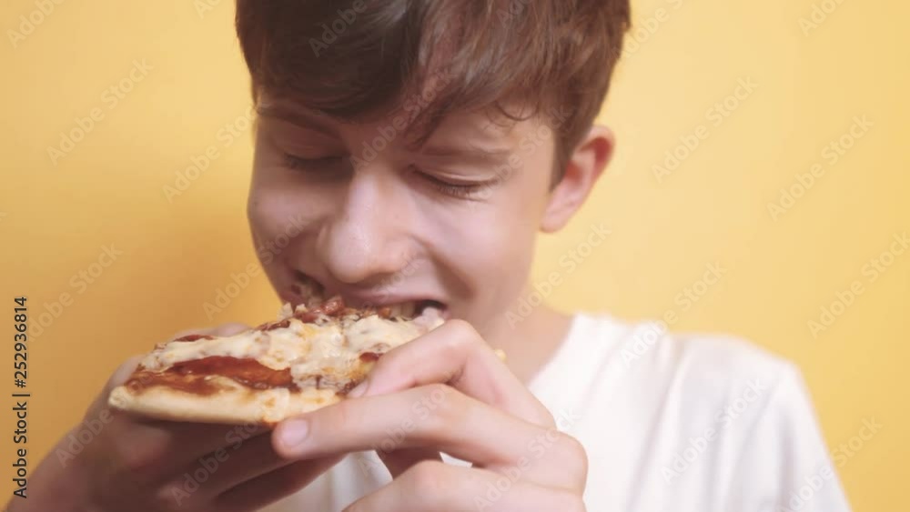 happy teen boy eating a slice of pizza concept. teenage boy lifestyle hungry eats a slice of pizza. slow motion video. pizza fast food concept happy teen boy eating a slice of pizza concept. teenage boy lifestyle hungry eats a slice of pizza. slow motion video. pizza fast food concept