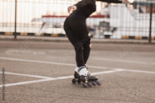 Woman skating by the sea. The girl goes rollerblading and does tricks. Caucasian woman outdoor at sunrise