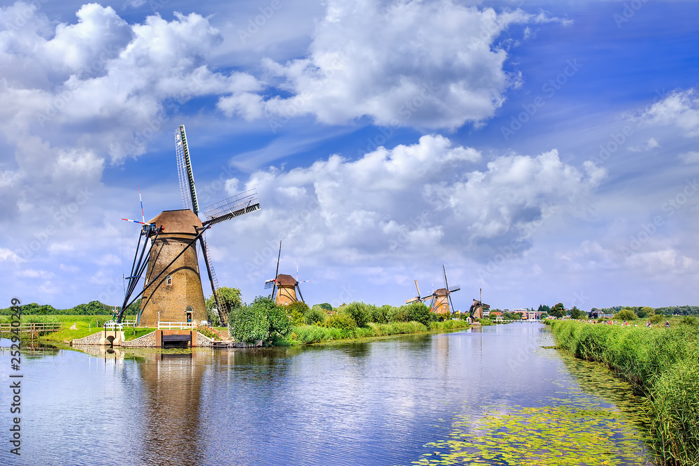 Ancient wind mills near a blue canal on a summer day at the famous Kinderdijk, Holland.