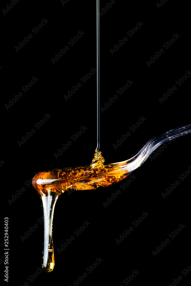 Honey falling on a spoon isolated on black background Honey falling on a spoon isolated on black background