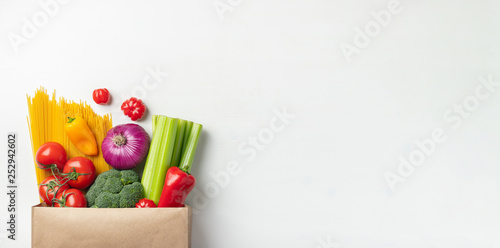 Paper bag of different healthy food on a table.