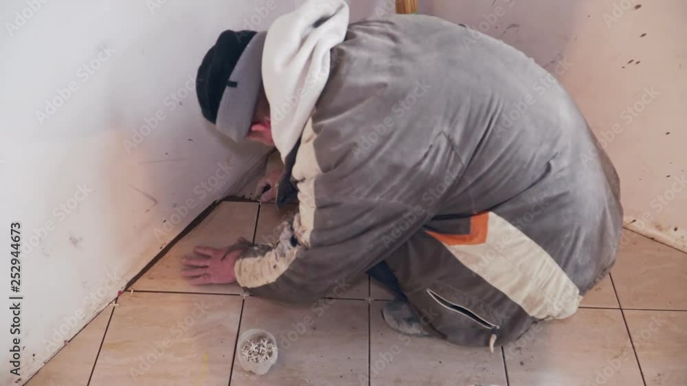 A tiler lays tiles on the floor A tiler lays tiles on the floor