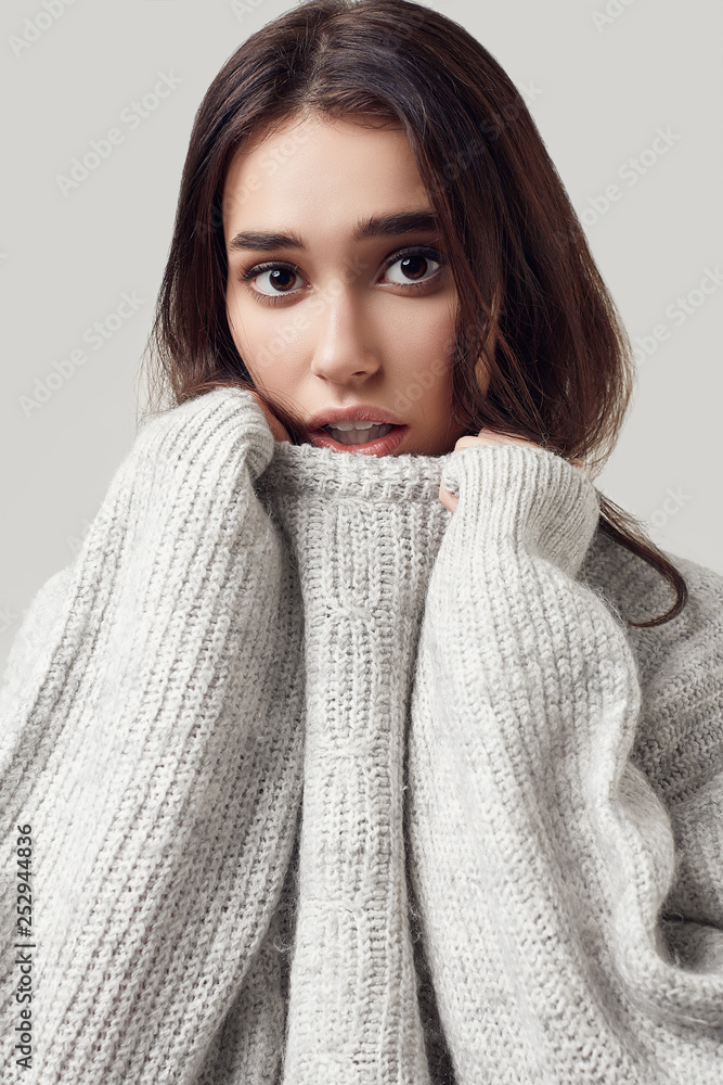 Beautiful brunette woman in sweater posing in studio Beautiful brunette woman in sweater posing in studio