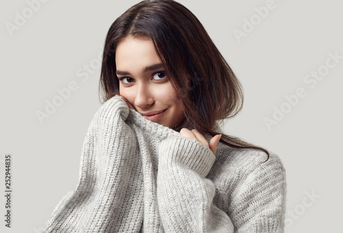 Beautiful brunette woman in sweater posing in studio photo