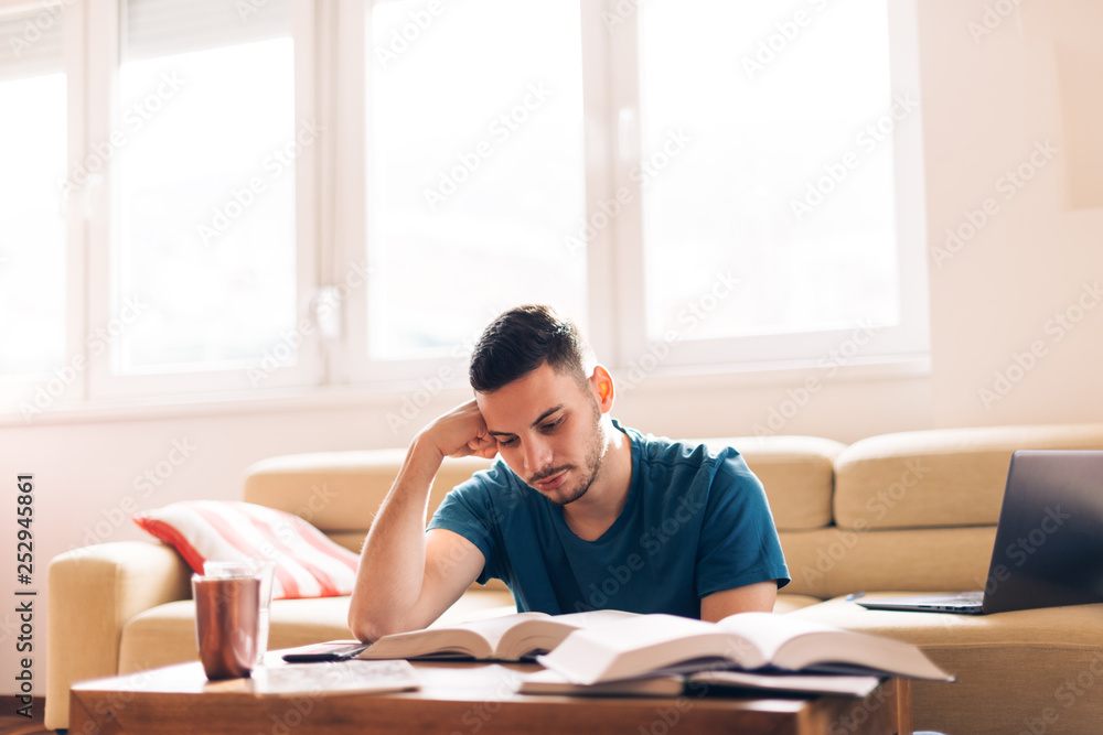 Handsome student studying with few opened books next to him. Handsome student studying with few opened books next to him.