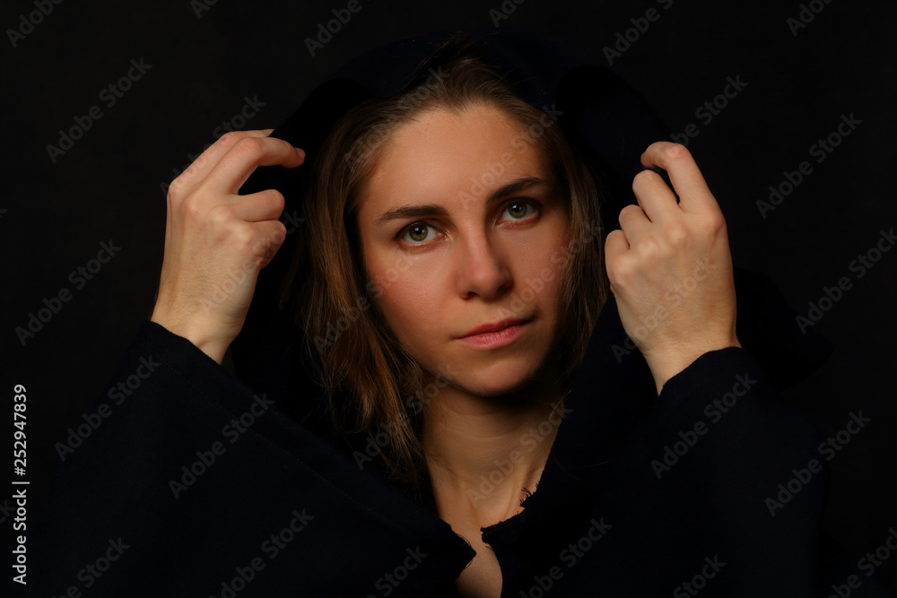 Young woman in a black cloak with a hood Young woman in a black cloak with a hood