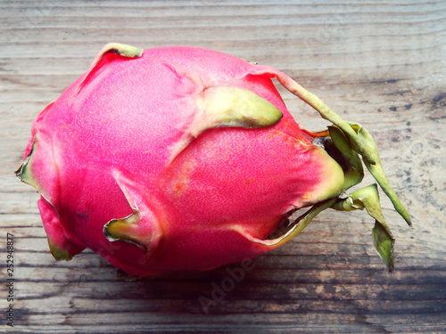 Juicy pink pitaya cut in two pieces on wooden table closeup