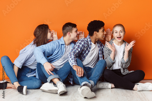Group of friends whispering each other in the ear
